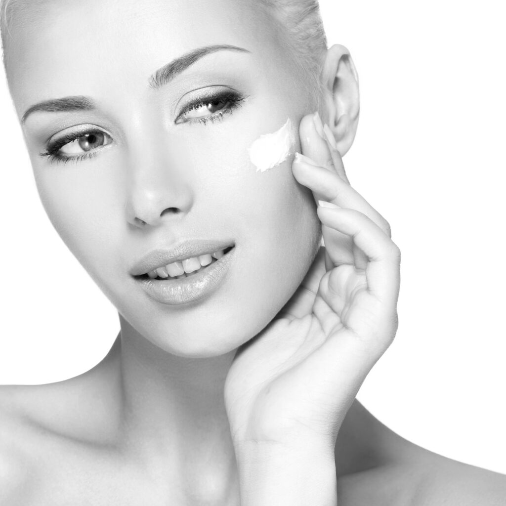 Young woman applying cosmetic  cream on a clean fresh face